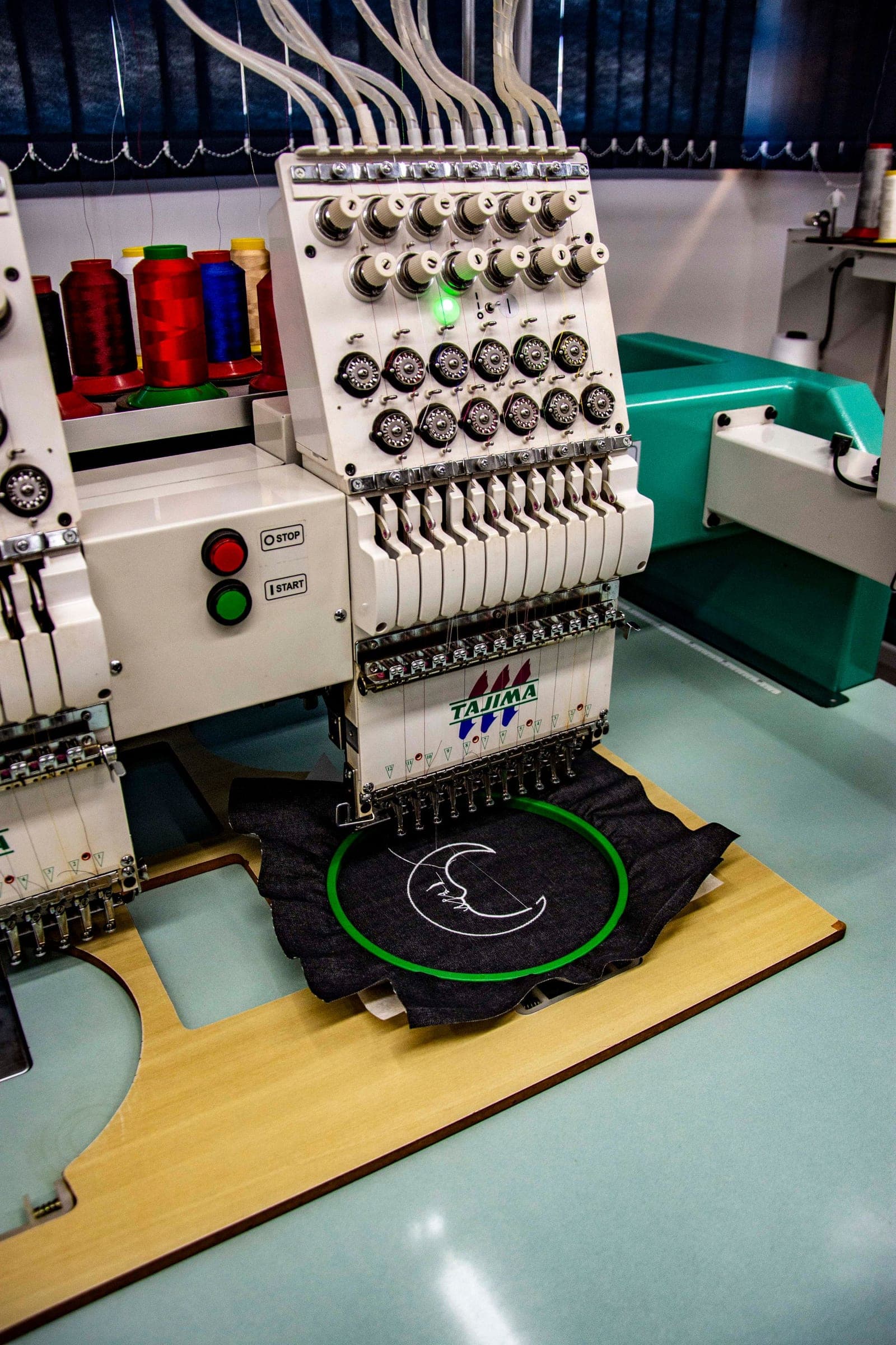 Stickmaschine bestickt dunklen Stoff mit einem Logo